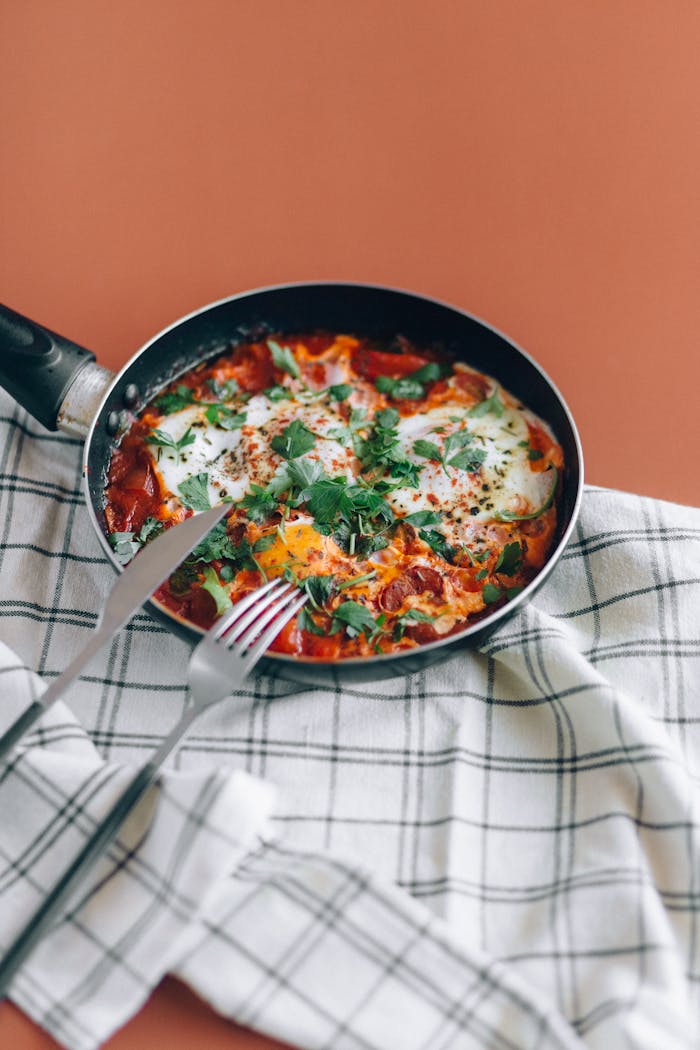 why-choose-us-01 Fresh shakshuka in a skillet with herbs on a table. Perfect for brunch.